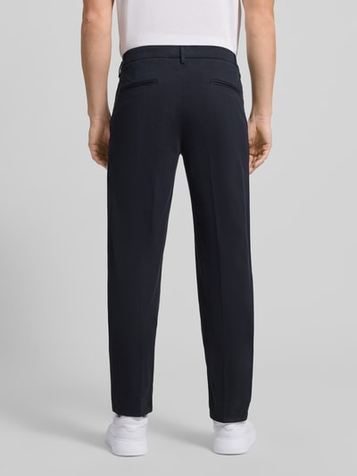 Männermodel trägt Relaxed Fit Hose mit Bügelfalten von Profuomo aus dunkelblauem Baumwoll-Elasthan-Mix, Gesäßtaschen, Ganzkörperansicht Rückansicht. Bundweite bei Größe 50: 45 cm, Innenbeinlänge: 84 cm.