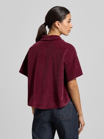 Frauenmodel trägt Cropped Hemdbluse mit Knopfleiste Modell 'PADOW' von American Vintage aus reiner Baumwolle in Dunkelrot, lockerer Schnitt, 1/2-Ärmel, Rückenansicht Ganzkörperansicht.