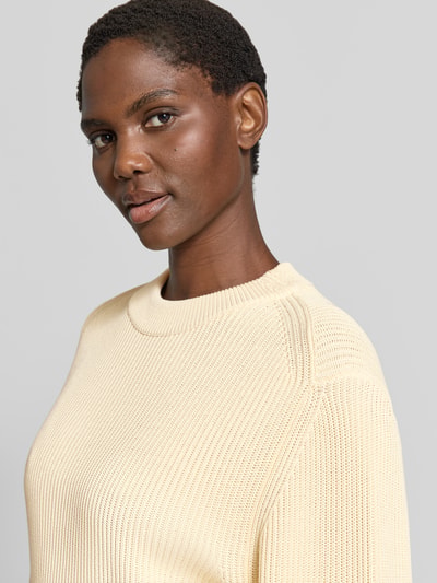 Frauenmodel trägt Relaxed Pullover mit Viskose-Anteil von Victoria Beckham in Creme, Strick-Optik, Rundhals, Nahaufnahme Oberkörper. Baumwoll-Mix, breite elastische Ärmelabschlüsse, relaxed Fit, glatte Textur.