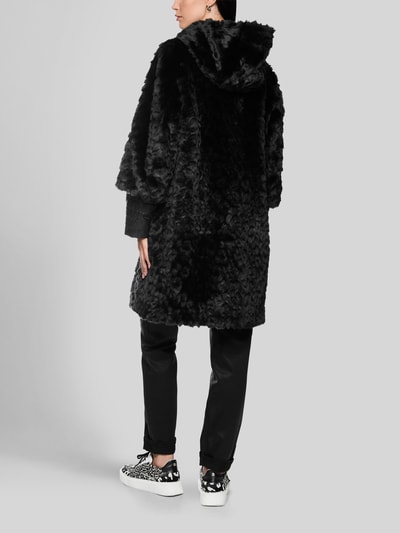 Frauenmodel trägt Mantel aus Kunstfell mit Zweiwege-Reißverschluss von Marc Cain, Regular Fit, schwarze, strukturierte Textur, Ganzkörperansicht Rückansicht. Rückenlänge 90 cm, Schulterbreite 43 cm, Brustweite 52 cm, Ärmellänge 63 cm.