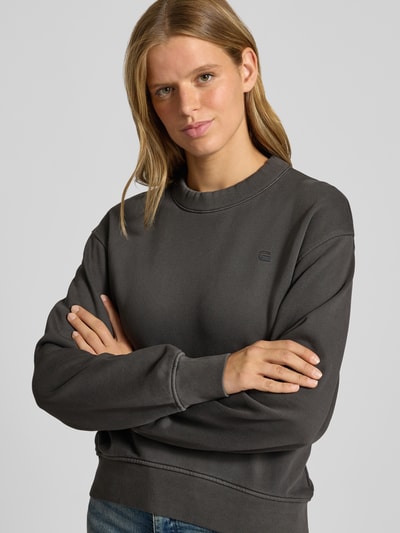 Frauenmodel trägt Relaxed Fit Sweatshirt aus reiner Baumwolle von G-Star RAW in Dunkelgrau, unifarben, Logo-Schriftzug, Nahaufnahme Oberkörper.