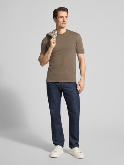 Männermodel trägt T-Shirt mit Rundhalsausschnitt von Drykorn in Braun, reine Baumwolle, Regular Fit, kombiniert mit Jeans, Ganzkörperansicht von vorne.