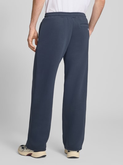 Männermodel trägt Straight Fit Sweatpants mit floraler Stickerei von REVIEW in Dunkelblau, Baumwoll-Mix, Rückansicht, Ganzkörperansicht.