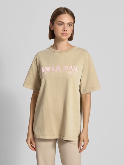 Frauenmodel trägt T-Shirt mit Rundhalsausschnitt Modell 'AM to PM' von OH APRIL, beige, lockerer Oversize-Schnitt, Print, reine Baumwolle, Ganzkörperansicht von vorne.