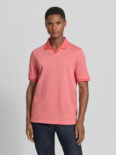 Männermodel trägt Regular Fit Poloshirt aus Baumwolle mit V-Ausschnitt von MAERZ Muenchen in Koralle, Label-Detail, Ganzkörperansicht von vorne. Rückenlänge bei Größe 50: 71 cm.