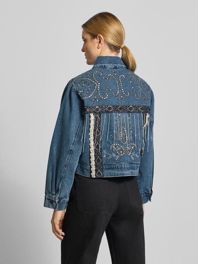 Frauenmodel trägt blaue Jeansjacke mit Perlen Modell 'VISION' von YAS, Regular Fit, reine Baumwolle, Detail auf Rückseite, Ganzkörperansicht Rückansicht.
