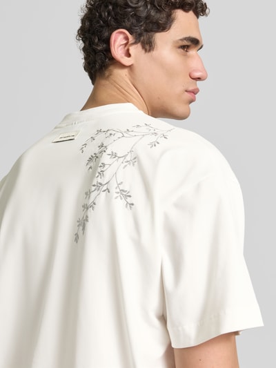 Männermodel trägt Relaxed Fit T-Shirt aus Baumwoll-Mix von Don’t Waste Culture mit Motiv-Print und Label-Print, Rückenlänge 70 cm, Nahaufnahme Oberkörper.