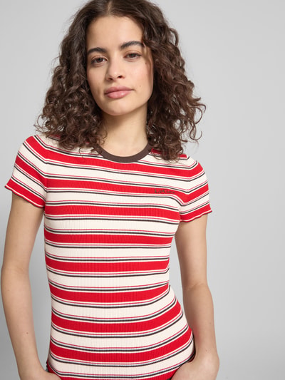 Kobieta nosi damski t-shirt z mieszanki wiskozy LeGer by Lena Gercke, dopasowany krój, drobne prążkowanie, wyhaftowane logo, model 'Danielle', okrągły dekolt, długość tyłu w rozmiarze 36: 50 cm, kolorowe paski; zbliżenie na górną część ciała, widok z przodu