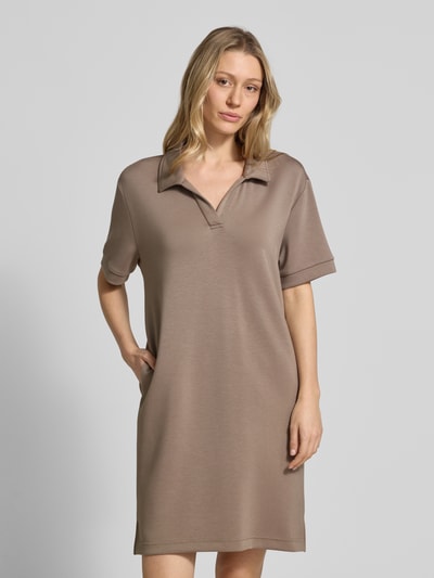 Modelka kobieca nosi Regular Fit Polokleid mit Modal-Anteil von Marc O'Polo, efekt: jednolity kolor, krój regular fit, długość mini, dekolt w serek, rękaw: krótki rękaw, boczne rozcięcia, mieszanka materiałów z dodatkiem modalu, całkowity przód.