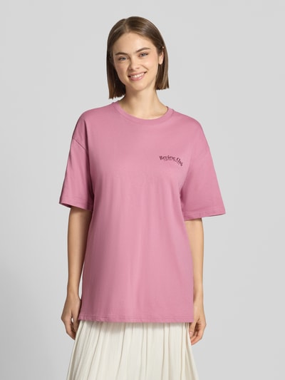 Frauenmodel trägt Oversized Fit T-Shirt aus reiner Baumwolle mit Label-Detail von REVIEW, rosa Farbe, glatte Textur, Ganzkörperansicht von vorne.