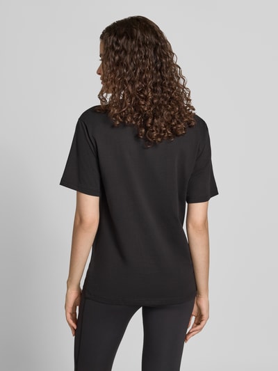 Frauenmodel trägt T-Shirt mit Label-Stitching und Rundhalsausschnitt von PUMA aus reiner Baumwolle im Regular Fit, schwarze Farbe, Ganzkörperansicht Rückansicht.