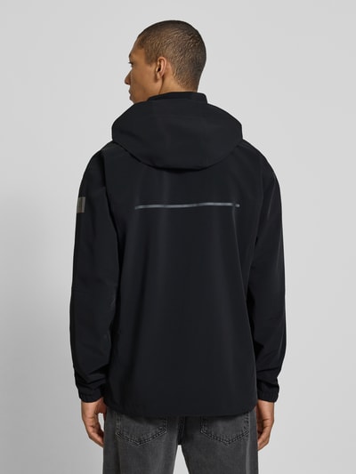 Männermodel trägt schwarze Jacke mit Kapuze, sichtbarem Reflexstreifen, FIRE + ICE, Jacke mit Zweiwege-Reißverschluss Modell 'YUPP-T', Ganzkörperansicht Rückansicht