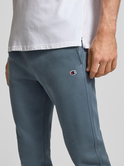 Männermodel trägt Sweatpants mit elastischem Bund und Label-Stitching von CHAMPION aus Baumwoll-Mix, Regular-Fit, Nahaufnahme Oberschenkel.