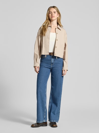 Frauenmodel trägt Cropped Jacke mit Eingrifftaschen von Jake*s Collection in Beige, reine Baumwolle, Knopfleiste, Umlegekragen, Ganzkörperansicht von vorne.