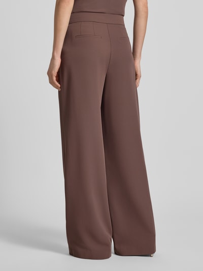 Männermodel trägt Wide Leg Stoffhose mit Raffungen von Christian Berg Cocktail, elastyczna mieszanka materiałów, zapięcie na haftkę i zamek błyskawiczny, marszczenia, szerokość w rozmiarze 36: 38 cm, długość wewnętrzna nogawki w rozmiarze 36: 82 cm, spodnie materiałowe, krój wide leg, kolor brązowy, gładka faktura, ganzkörperansicht rückansicht.