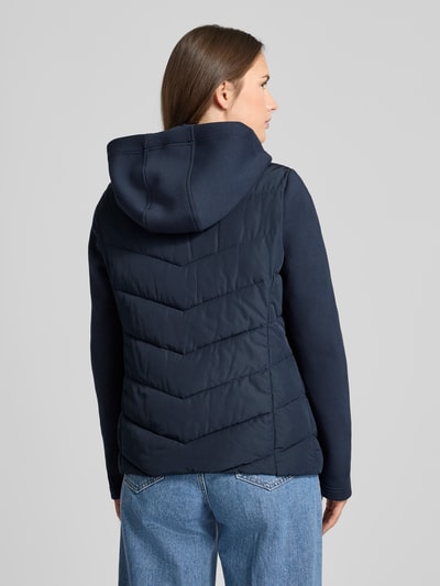 Vrouwenmodel draagt Slim Fit Steppjacke met gefüttertem Stehkragen van Christian Berg Woman Selection, donkerblauw, gestept patroon, met capuchon en ritszakken, ganzebodyaanzicht achterkant.
