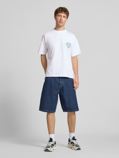 Männermodel trägt weißes Herren T-Shirt mit Statement-Print Modell 'Sunday Running Club' von ANOTHER COTTON LAB aus Reine Baumwolle, Boxy-Fit, Rundhalsausschnitt, Rückenlänge bei Größe M: 69 cm, Ganzkörperansicht von vorne.