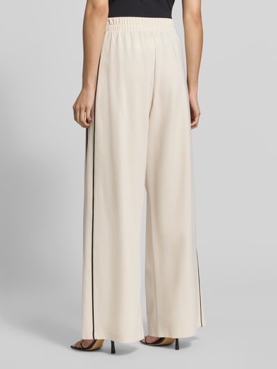 Frauenmodel trägt Relaxed Fit Weite Hose aus Lyocell-Mix Modell 'GODEZIA' von Weekend Max Mara in Creme mit schwarzem Seitenstreifen, Ganzkörperansicht Rückansicht, Damen Weite Hose von Max Mara.