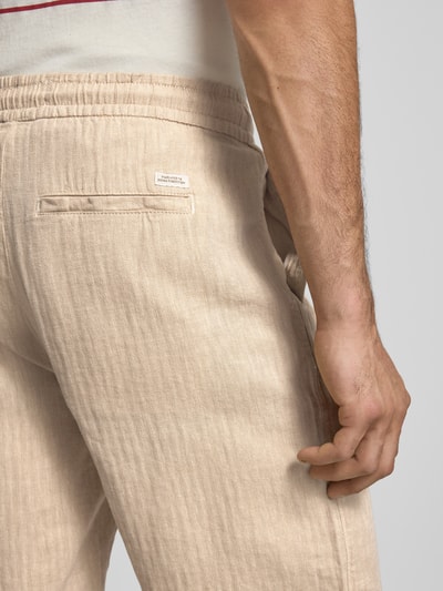 Männermodel trägt Shorts aus Leinen-Mix mit Eingrifftaschen Modell 'MARCO' von Blend, natürliche Beige-Töne, strukturierte Oberfläche, Nahaufnahme Rückansicht, Herren Shorts aus Leinen-Baumwoll-Anteil, Straight Fit, elastischer Bund mit Kordelzug, Gesäßleistentasche, Bundweite 39 cm, Innenbeinlänge 25 cm bei Größe M.