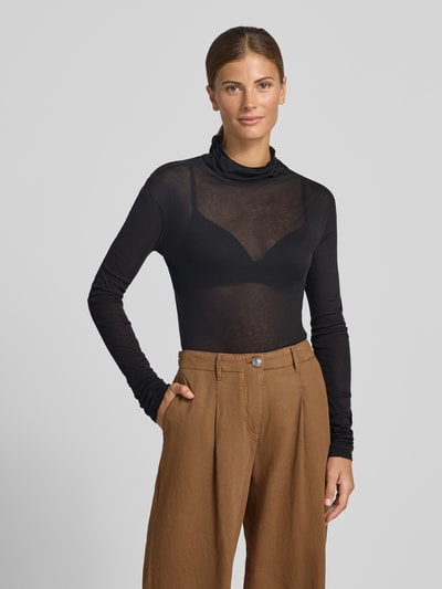 Kobiece modelka nosi Slim Fit Rollkragenshirt aus reiner Baumwolle von American Vintage, czarna, prążkowana, ozdobne szwy, krój slim fit, długość tyłu w rozmiarze S: 68 cm, bluzka z długim rękawem, widok całej sylwetki z przodu.