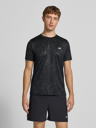 Männermodel trägt schwarzes T-Shirt mit Logo-Print Modell 'ESSENTIAL' von New Balance, gerader Schnitt, Rundhalsausschnitt, glatte Struktur, Ganzkörperansicht von vorne.