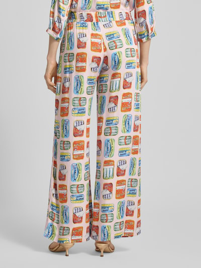 Frauenmodel trägt Relaxed Fit Stoffhose aus reiner Viskose von Milano Italy mit buntem Print, elastischem Smok-Bund und Eingrifftaschen, Ganzkörperansicht Rückansicht.