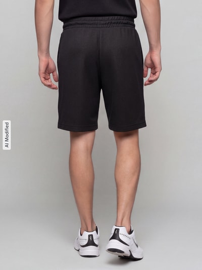 Männermodel trägt Relaxed Fit Sweatshorts aus Baumwoll-Mix 'ESS ELEVATED' von PUMA, Herren Sweatshorts, Ganzkörperansicht Rückansicht, KI-modifiziertes Bild.
