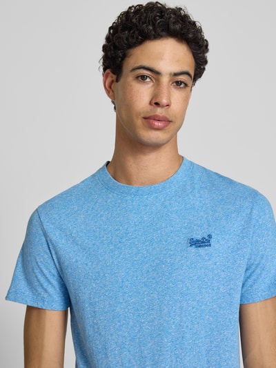 Männermodel trägt Regular Fit T-Shirt mit Logo-Stitching von Superdry aus Reine Baumwolle, meliertes Hellblau, Rundhalsausschnitt, Nahaufnahme Oberkörper.