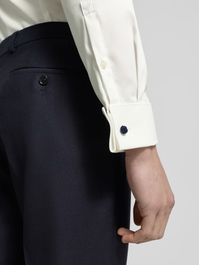 Männermodel trägt Regular Fit Smokinghemd aus Feintwill von Jake*s, Kentkragen, Sportmanschette, weiße feine Webstruktur, Nahaufnahme Unterarm.