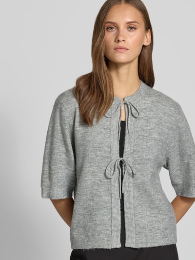 Frauenmodel trägt Regular Fit Strickjacke mit Schnürung Modell 'SIMONI' von ONLY, hellgrau meliert, Damen Pullover, Nahaufnahme Oberkörper.