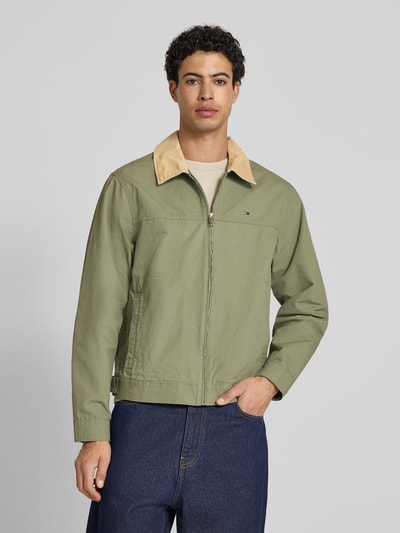 Męski model nosi Regular Fit Blouson aus reiner Baumwolle von Tommy Jeans, jednolity kolor, wykładany kołnierz, zamek błyskawiczny, wyhaftowane logo, pas na plecach, patki, długi rękaw z mankietami, wpuszczane kieszenie, flammgarn, bawełna. Ganzkörperansicht von vorne.