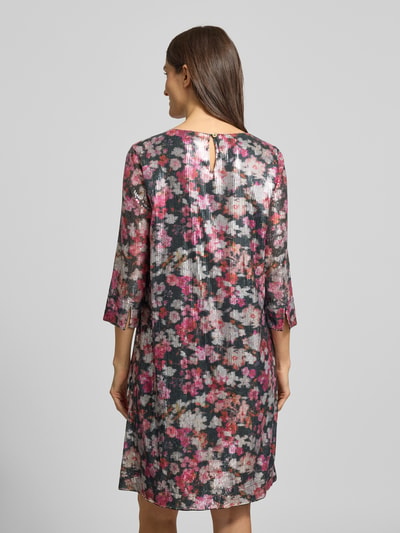 Frauenmodel trägt Knielanges Kleid mit Allover-Muster und Paillettenbesatz von Christian Berg Woman aus czystej wiskozy, prosty krój, długość do kolan, kwiatowy wzór na całej powierzchni, okrągły dekolt, rękaw o dł. 3/4, cekinowe obszycie, długość tyłu w rozmiarze 36: 96 cm, szerokość w rozmiarze 36: 48 cm, długość rękawa w rozmiarze 36: 47 cm, odcienie różu, czerni i bieli, tekstura lekko prześwitująca, kwiatowy print, całkowity widok z tyłu.