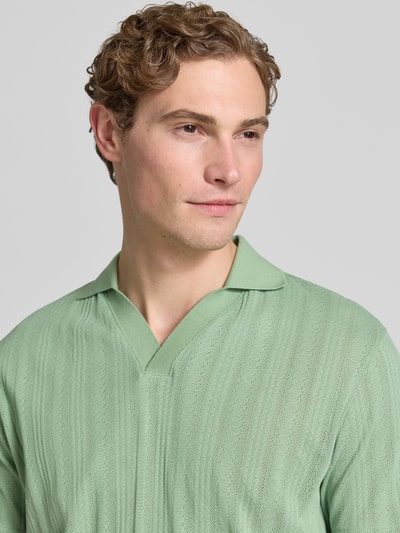 Männermodel trägt Regular Fit Poloshirt aus Baumwoll-Mix Modell 'TRAVIS' von SELECTED HOMME in Optik: Unifarben mit Struktur, Polokragen, V-Ausschnitt, kurze Knopfleiste, Jacquard-Materialverarbeitung, Farbe hellgrün, Nahaufnahme Oberkörper.