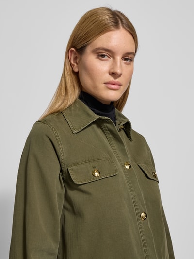 Frauenmodel trägt Regular Fit Jacke mit Umlegekragen von Anine Bing aus reiner Baumwolle in Oliv mit Knopfleiste und Pattentaschen, Nahaufnahme Oberkörper.