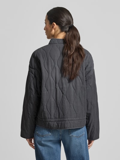 Frauenmodel trägt Steppjacke aus Lyocell-Baumwoll-Mix mit Stehkragen von Jake*s Casual in Anthrazit, wellige Steppung, Rückenansicht, Ganzkörperansicht Rückansicht, Regular Fit, Knopfleiste, Eingrifftaschen, Rückenlänge 59 cm, Schulterbreite 45 cm, Brustweite 60 cm, Ärmellänge 49 cm.