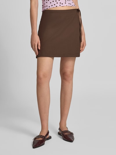 Vrouwenmodel draagt Körpernaher Mini-Rock in Wickel-Optik Modell 'BOSELLA' van PIECES in effen bruin, gladde textuur, Dames Minirok, vooraanzicht volledige lichaamsopname.