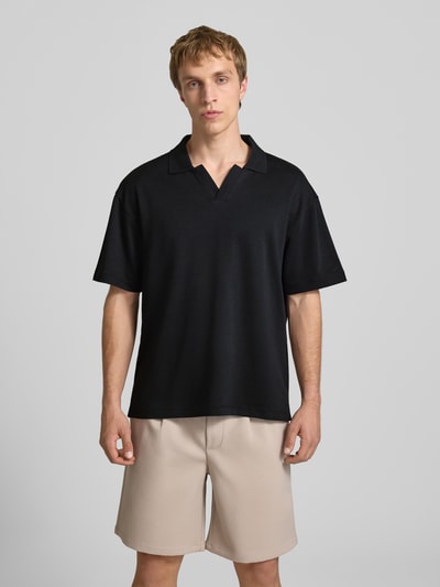 Männermodel trägt Boxy Fit Poloshirt aus Baumwoll-Mix Modell 'CASPIAN AIRLEX' von Only & Sons in Schwarz, unifarben, Ganzkörperansicht von vorne.