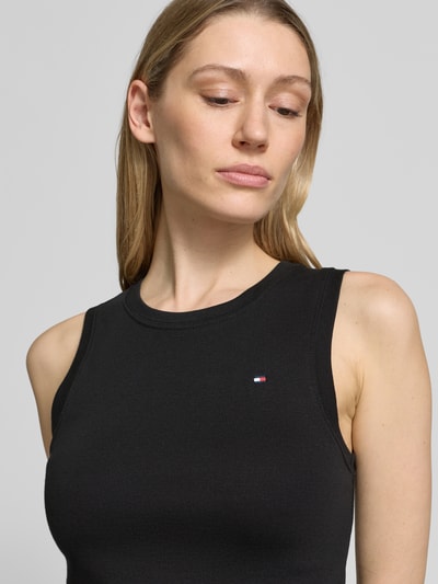 Frauenmodel trägt Slim Fit Tank Top aus reiner Baumwolle Modell 'SLIM CODY' von Tommy Hilfiger in Optik: Unifarben mit Logo-Stitching, Rundhals-Ausschnitt und breite Träger, Nahaufnahme Oberkörper.