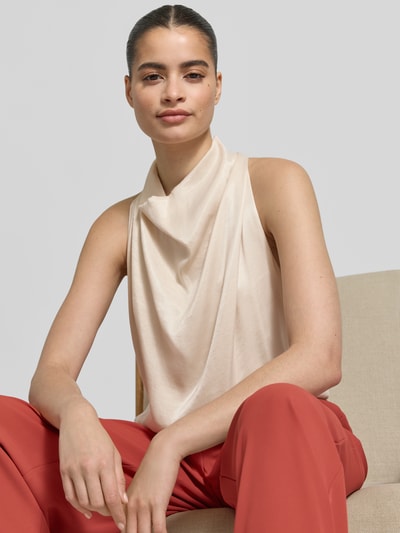 Frauenmodel trägt Blusenshirt aus Viskose-Mix mit Wasserfall-Ausschnitt von Jake*s Collection in Beige, glatte Textur, rote Hose, Nahaufnahme Oberkörper, Straight Fit, rückseitiger Schlüsselloch-Ausschnitt, Rückenlänge bei Größe 36: 60 cm.
