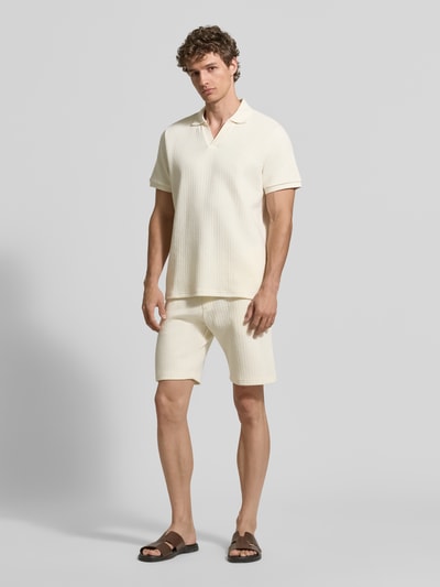 Männermodel trägt Regular Fit Strick-Poloshirt mit V-Ausschnitt von MCNEAL aus cremefarbenem Baumwoll-Mix mit Stretch-Anteil, Ganzkörperansicht von vorne. Rückenlänge bei Größe M: 70 cm.