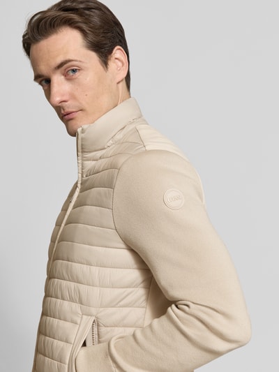 Männermodel trägt Regular Fit Jacke in Stepp-Optik von Colmar Originals in Beige mit Stehkragen, Nahaufnahme Oberkörper.