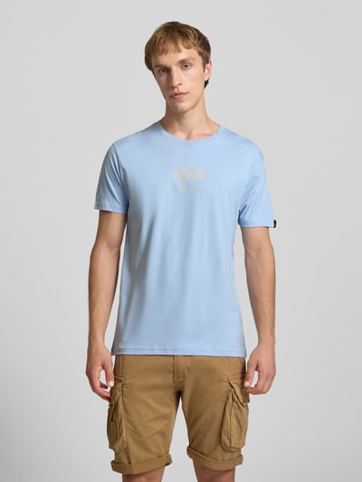 Männermodel trägt T-Shirt mit Logo und Rundhalsausschnitt von Alpha Industries in Hellblau, Regular-Fit, Reine Baumwolle, Ganzkörperansicht von vorne. Rückenlänge bei Größe M: 67 cm.