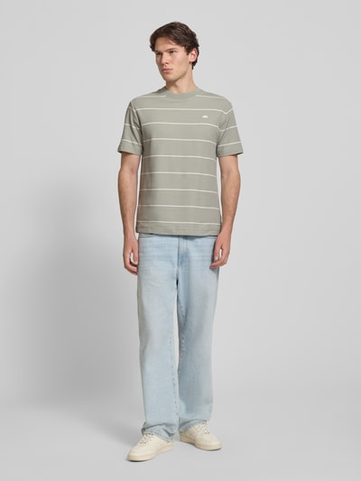 Männermodel trägt Herren T-Shirt mit Label-Stitching Modell 'VERRI' von ellesse, gestreifter Allover-Look, Baumwoll-Mix, Regular-Fit, Rundhalsausschnitt, Rückenlänge bei Größe M 67 cm, helle Farben, glatte Textur, Ganzkörperansicht von vorne.