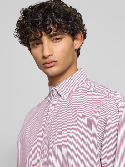 Męski model nosi Regular Fit Freizeithemd mit Brusttasche Modell 'NORREBRO' od Jack & Jones, bawełniana mieszanka, krój regular fit, kołnierzyk button-down, lista guzikowa, kieszeń na piersi, długość pleców w rozmiarze M: 74 cm, szerokość w rozmiarze M: 52 cm, długość rękawa w rozmiarze M: 60 cm, biało-bordowe, drobne paski, tekstura gładka, zbliżenie na górną część ciała