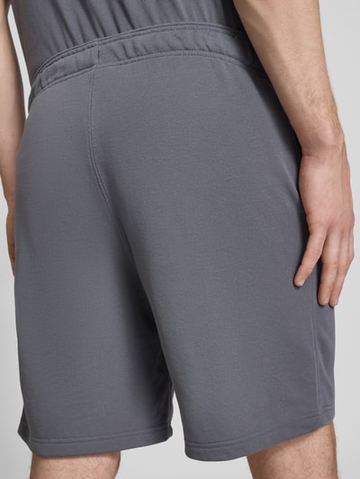 Mannenmodel draagt Shorts mit elastischem Bund und Label-Stitching van CHAMPION in grijze katoenmix, regular fit, detailopname rugaanzicht.