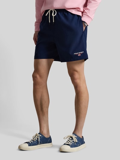 Männermodel trägt Zwembroek met labelstitching van Polo Ralph Lauren, effen kleuren, tunnelkoord, elastische boord, steekzakken en achterzak. Detailaufnahme.