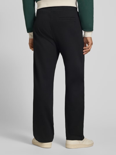 Männermodel trägt Straight Fit Sweatpants mit elastischem Bund von REVIEW, Mieszanka materiałów z mieszanką bawełny, Kanty, Szerokość w rozmiarze M: 42 cm, Długość wewnętrzna nogawki w rozmiarze M: 82 cm, czarne spodnie dresowe, widoczne tekstury materiału, Ganzkörperansicht Rückansicht.