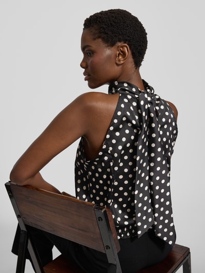 Frauenmodel trägt Blusentop im Allover-Look von Neo Noir in Schwarz mit weißen Punkten, Stehkragen und rückseitiger Schnürung, Regular Fit, Rückenlänge bei Größe 36: 50 cm, Ganzkörperansicht Rückansicht.