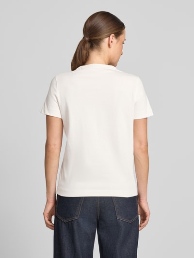 Kobiece model nosi damski t-shirt z bawełny o kroju regular fit, T-Shirt mit Logo aus Perlen od GUESS, okrągły dekolt, długość tyłu w rozmiarze S: 58 cm, widok całej sylwetki z tyłu.