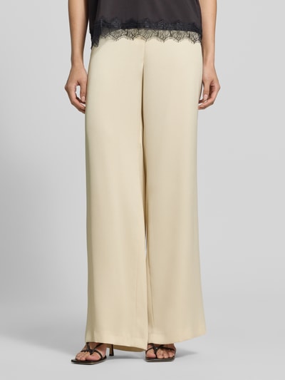 Frauenmodel trägt Wide Fit Hose mit Bundfalten von SWING in Beige, locker fallender Stoff, taschenloses Design, Nahaufnahme Unterkörper. Innenbeinlänge 82 cm, Bundweite 38 cm, Haken- und Reißverschluss.